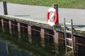 Lifebuoy rescue circle on the embankment near ladder stairs into water in the city on lake during sunny day Royalty Free Stock Photo