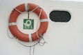 A lifebuoy, ring buoy, lifering, life donut, life preserver on the white wall of boat or yacht Royalty Free Stock Photo