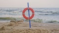 Lifebuoy Ring Hanging on Pole at Seaside Beach on Windy Day with Rough Sea High Waves Royalty Free Stock Photo