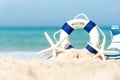 Lifebuoy on sand beach background with starfish and fishing boat