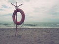 Lifebuoy on a sandy beach. Orange circle on a pole to rescue people drowning in the sea. Rescue point on the shore. Sky Royalty Free Stock Photo