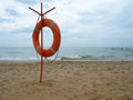 Lifebuoy on a sandy beach. Orange circle on a pole to rescue people drowning in the sea. Rescue point on the shore. Sky Royalty Free Stock Photo