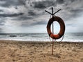 Lifebuoy on a sandy beach. Orange lifebuoy on a pole to rescue people drowning in the sea. Rescue point on the shore Royalty Free Stock Photo