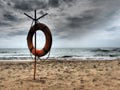 Lifebuoy on a sandy beach. Orange lifebuoy on a pole to rescue people drowning in the sea. Rescue point on the shore Royalty Free Stock Photo