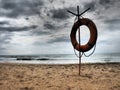 Lifebuoy on a sandy beach. Orange lifebuoy on a pole to rescue people drowning in the sea. Rescue point on the shore Royalty Free Stock Photo