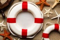 Lifebuoy, ship`s steering wheel and various starfish on beach