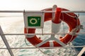 Lifebuoy with sign on a ferry fence, with sun and sea in backgro Royalty Free Stock Photo