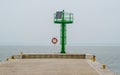 Lifebuoy stand and a green port header in a small harbor Royalty Free Stock Photo
