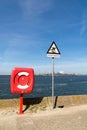 Lifebuoy and warning sign at quay of North Sea Canal in IJmuiden near Amsterdam, Netherlands