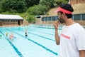 Lifeguard blowing whistle while students playing in pool