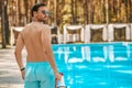 A lifeguard in blue shorts standing near the swimming pool