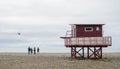 Lifeguard booth on the beach. The beach is out of season. People on the beach next to a wooden structure