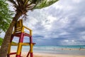 Lifeguard chair near the coconut tree on the beach with a rain cloud. Royalty Free Stock Photo