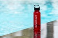 lifeguard drinking bottle next to bright blue pool. Royalty Free Stock Photo