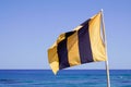 Lifeguard flag yellow line black on beach ocean coast in blue sea and sky Royalty Free Stock Photo