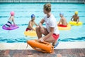 Lifeguard holding rescue can while children swimming in pool