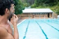 Lifeguard looking at swimming pool and blowing whistle Royalty Free Stock Photo