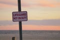 Lifeguard Not On Duty sign posted at ocean view of sunset