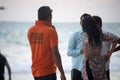 lifeguard in orange shirt carrying flag along the beach with tourists in background at havelock swaraj dweep andaman