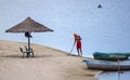 The lifeguard removes the sandy beach with umbrellas, on the river bank there are boats with the inscription `Rescue`.