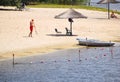 The lifeguard removes the sandy beach with umbrellas, on the river bank there are boats with the