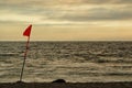 A lifeguard`s flag in the afternoon light of an overcast beach.