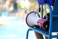 lifeguard sitting on chair with megaphone at poolside for guarding lives Royalty Free Stock Photo