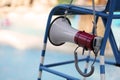 lifeguard sitting on chair with megaphone at poolside for guarding lives Royalty Free Stock Photo