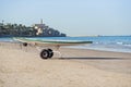 Lifeguard surf rescue surfboard with oars on the stand with wheels on sand beach close the sea.