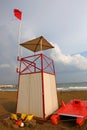 Lifeguard tower on the beach with the red flag fluttering in the Royalty Free Stock Photo