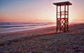 Lifeguard tower, sunrise, footprints on secluded beach with mountains and calm sea, playa de muro, alcudia, mallorca, spain