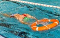 Lifeguard training in swimming pool. Man with lifeguard float swimming in an indoor pool in Spain.