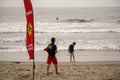 A lifeguard at Ventura Harbor watches swimmers in front of a warning sign advising of