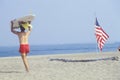 Lifeguard walking past an American flag planted in the sand, Lake Erie, Pennsylvania