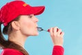 Lifeguard woman in cap on duty whistling.