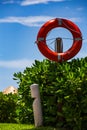 Lifeguards preserver tube hanging on wooden post on summer beach day