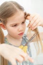 Little girl cutting hair to herself with scissors Royalty Free Stock Photo