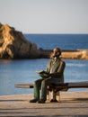 Bronze Statue of a Man Reading a Book on a Bench by the Sea of Costa Brava in Blanes. La Palomera. Carl Faust Royalty Free Stock Photo