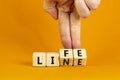 Lifeline, line of life symbol. Businessman hand turns cubes and changes the word `life` to `line`. Beautiful orange background Royalty Free Stock Photo