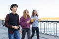 Lifestyle of adolescents, boy and two teen girls are walking in the city. Laughing, talking children eating street food, having Royalty Free Stock Photo