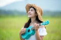 Lifestyle asian women white dress holding a guitar on a cloudy sunrise sky in the meadow flower, Royalty Free Stock Photo