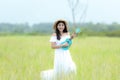 Lifestyle asian women white dress holding a guitar on a cloudy sunrise sky in the meadow flower, relax Royalty Free Stock Photo