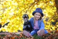 Lifestyle autumn photo, little girl and miniature schnauzer dog walking outdoors. Royalty Free Stock Photo