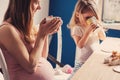 Lifestyle capture of pregnant mother and baby girl having breakfast and drinking tea at home