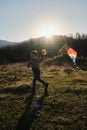 Lifestyle concept. Catch rays of departing sun. Little Caucasian boy runs around field with kite at sunset. Have fun spending
