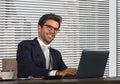 Lifestyle corporate company portrait of young happy and successful business man working relaxed at modern office sitting by window