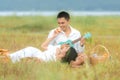 Lifestyle couple picnic sunny time. Asian young couple having fun and relax playing guitar on picnic in the meadow and field in ho