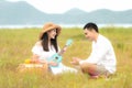 Lifestyle couple picnic sunny time. Asian young couple having fun and relax playing guitar on picnic in the meadow and field in ho Royalty Free Stock Photo