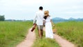 Lifestyle couple picnic sunny time. Asian young couple having fun and walking relax in the meadow and field in holiday.