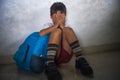 Young sad scared kid 8 years old in school uniform and backpack sitting alone crying depressed and frightened suffering abuse prob Royalty Free Stock Photo